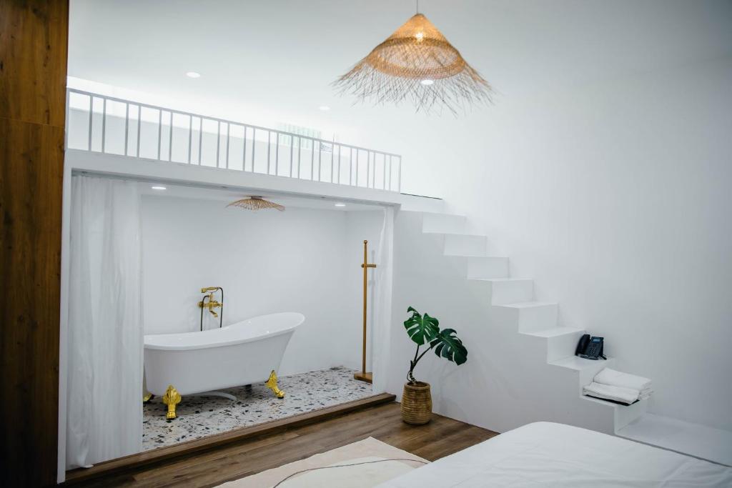 een witte badkamer met een bad en een trap bij Pisces Hotel Hue in Hue
