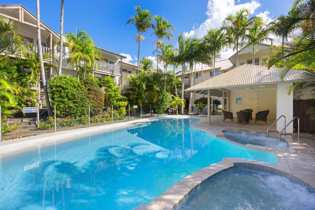 a swimming pool at a resort with palm trees at Noosa Outrigger Beach Resort in Noosaville