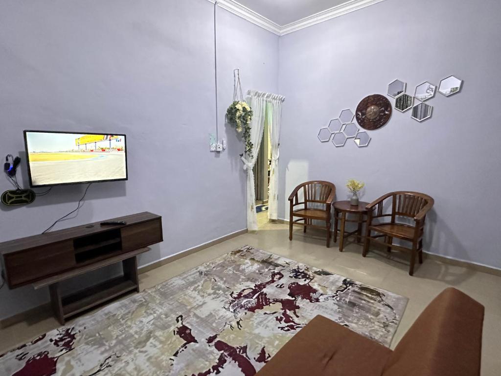 uma sala de estar com uma televisão e uma mesa em Raudah Homestay em Kota Bharu