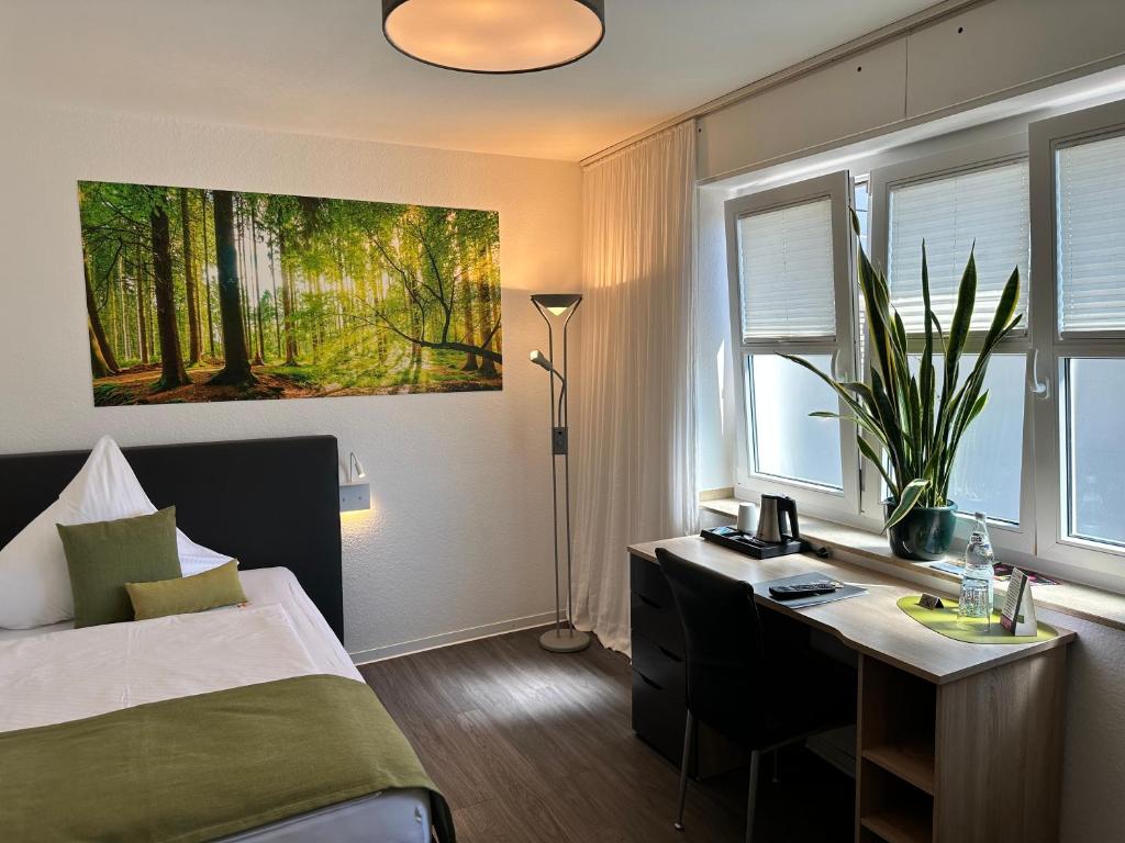 Schlafzimmer mit einem Bett, einem Schreibtisch und einem Fenster in der Unterkunft an Hotel in Selm