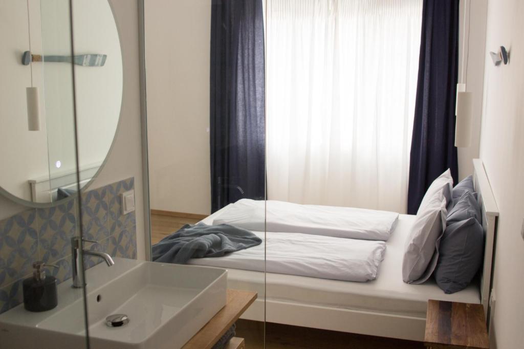 bagno con letto, lavandino e specchio di Pannonia Apartments a Mörbisch am See