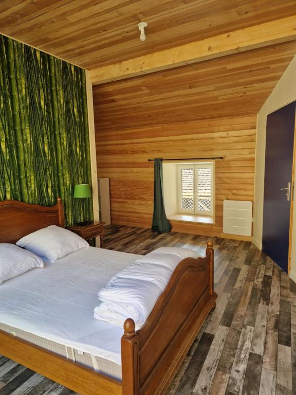 a bedroom with a bed with a wooden wall at Gîte des Catalpas in Vollore-Ville