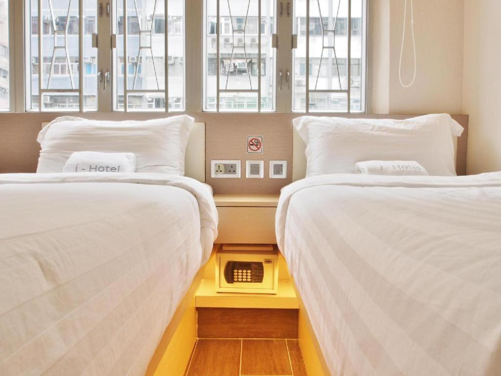 2 camas con sábanas blancas en una habitación con ventanas en i hotel-B&B en Hong Kong