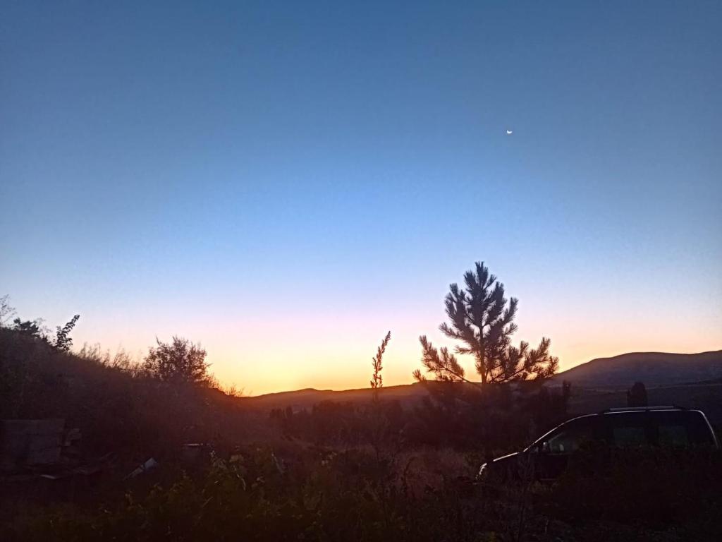 einen Sonnenuntergang in den Bergen mit einem Auto auf dem Feld in der Unterkunft KIR EVI/BAG EVI 