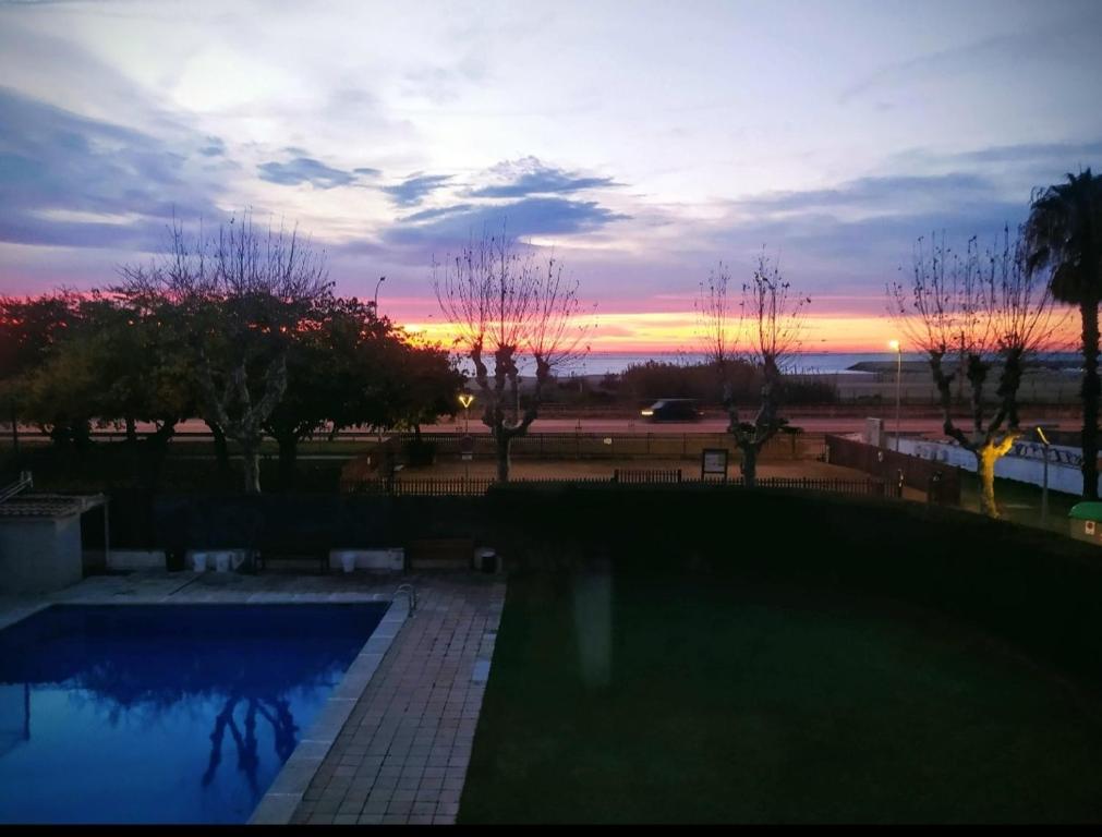 プレミア・デ・マルにあるSuite en 1a línea de Playa con piscina a 20 minutos de Barcelonaの庭のスイミングプールに沈む夕日