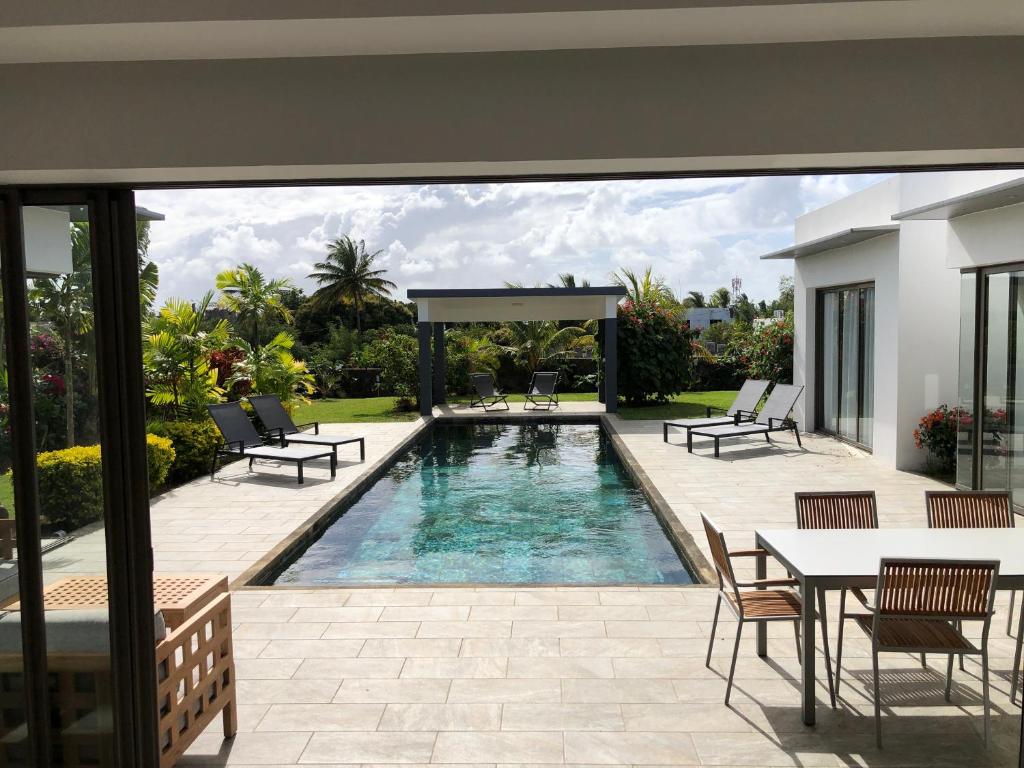 una piscina en un patio trasero con mesa y sillas en L'Escapade la Villa de vos prochaines vacances, en Cap Malheureux