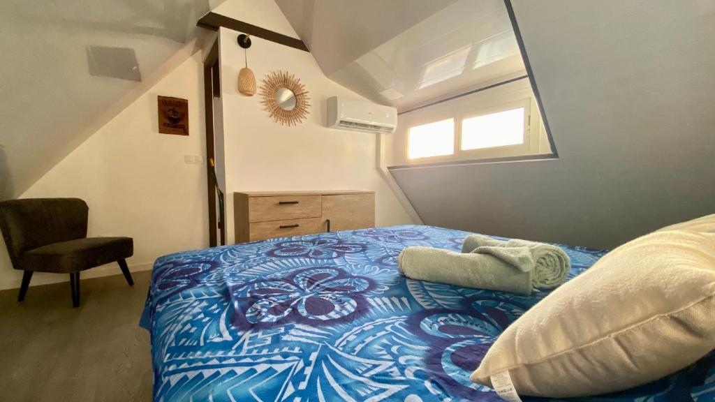 a bedroom with a bed with a blue comforter and a window at Vanakea Beach House in Punaauia