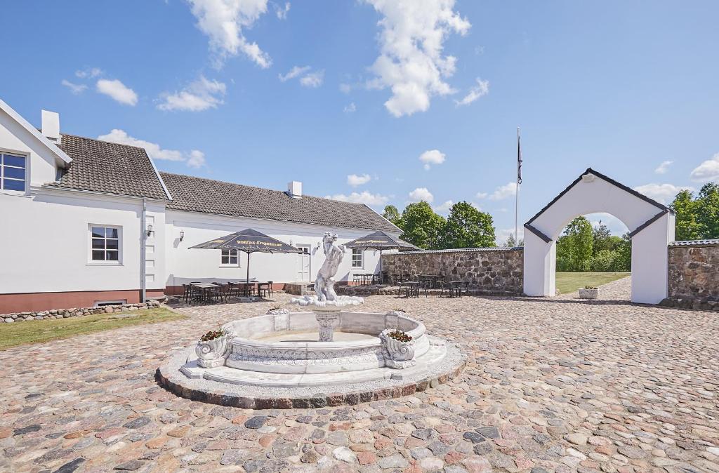 a fountain in the middle of a courtyard in front of a house at Arklių Pašto Stotis 