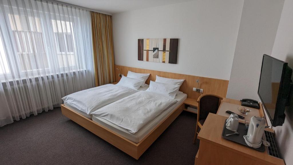 a bedroom with a bed and a desk and a television at Gästehaus Ziegler in Stuttgart