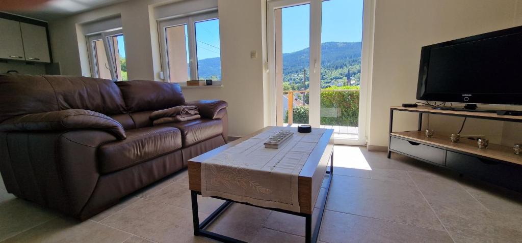 Una sala de estar con un sofá y una mesa de café. en Gîte moderne et calme avec local séparé pour skis et vélos, en Cornimont