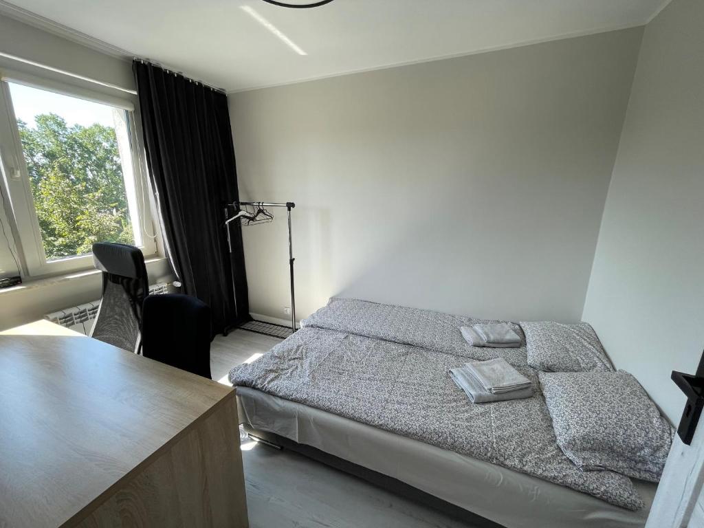 a bedroom with a bed and a desk and a window at Apartament na Broniewskiego in Gdańsk