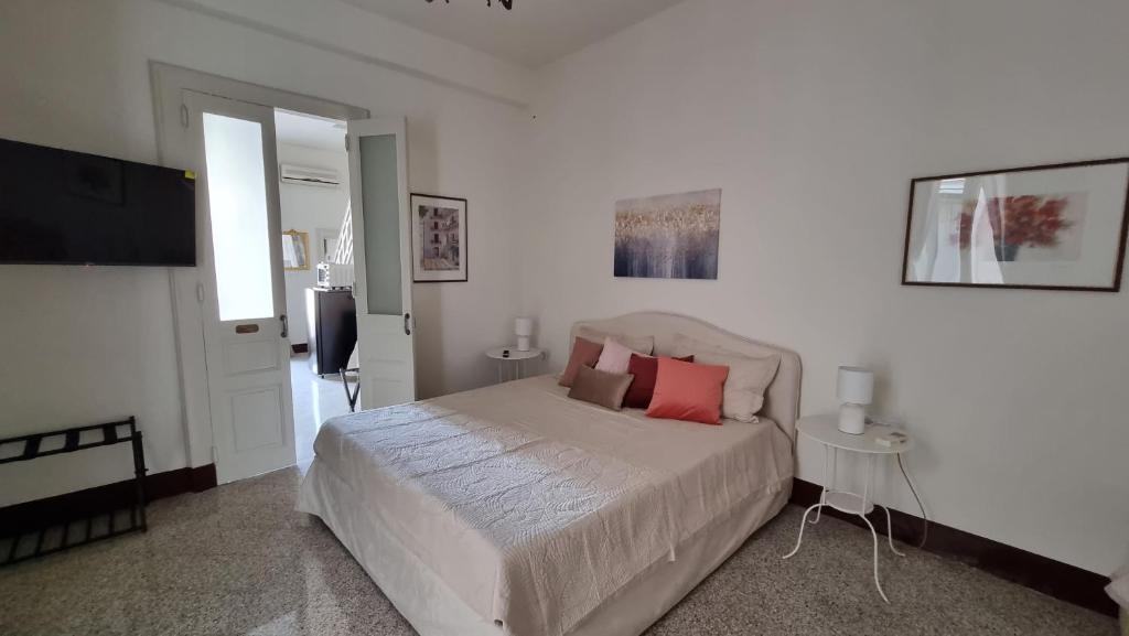 een witte slaapkamer met een groot bed met rode kussens bij Le Dimore del Corso I ad Acireale fra Catania, Taormina, il Mare e l'Etna in Acireale