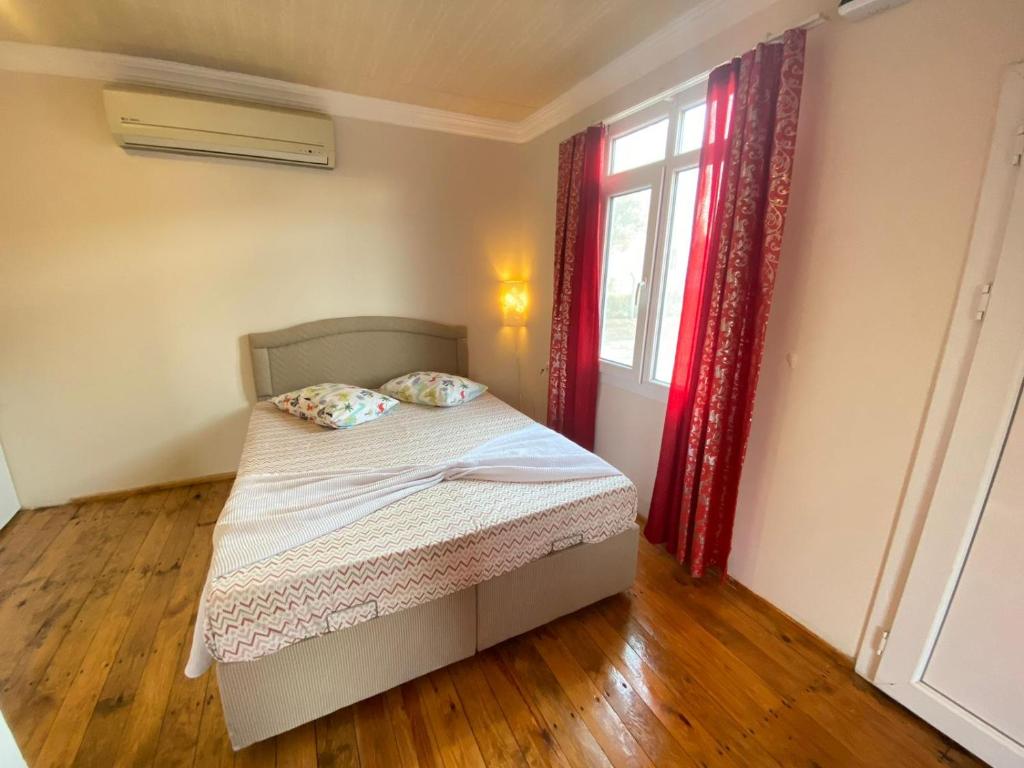 a bedroom with a bed and a window with red curtains at Reds Bungalow in Didim