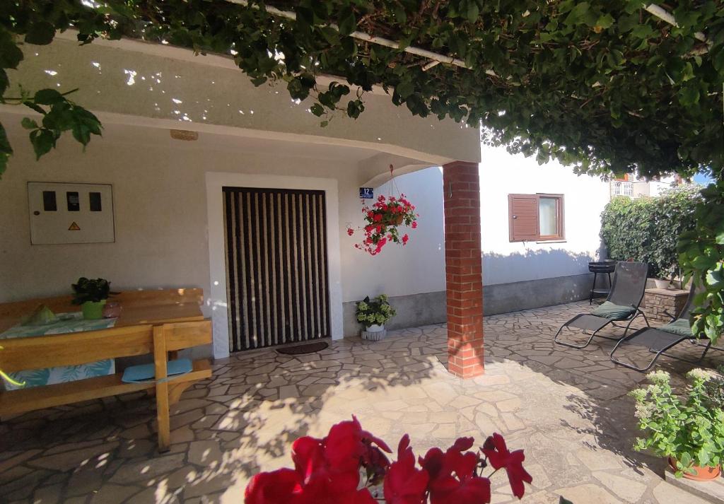 a house with a porch with a bench and red flowers at Apartman CELIJA in Barban
