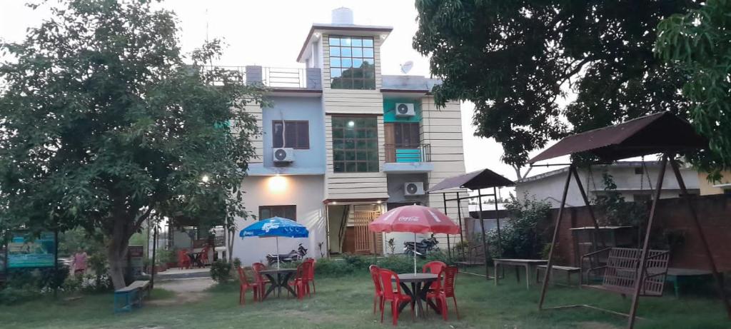 a group of chairs and tables in front of a building at Corbett Rejoice Home Stay in Jhirna