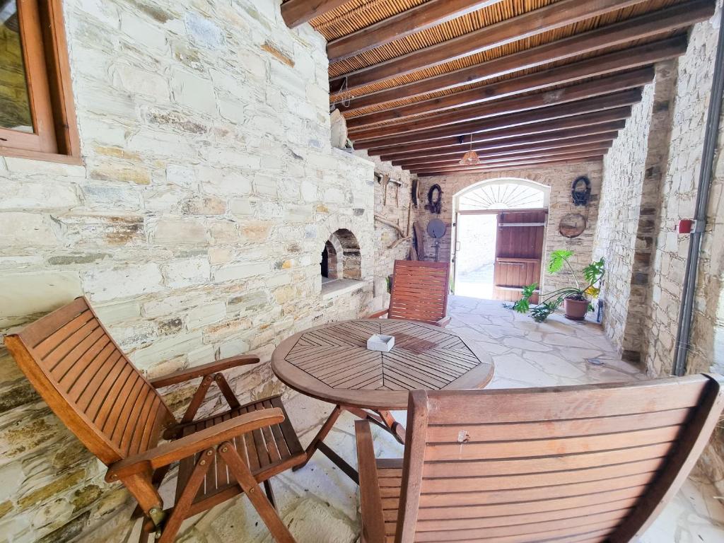 un patio con mesa y sillas en una pared de piedra en Skarinou's Landhouse Poolside Heaven Apartment, en Skarinou
