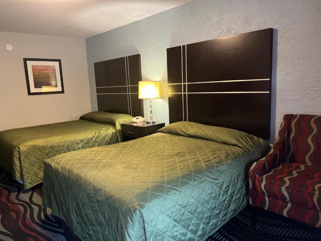 a hotel room with two beds and a chair at Applegate Inn in Cleveland