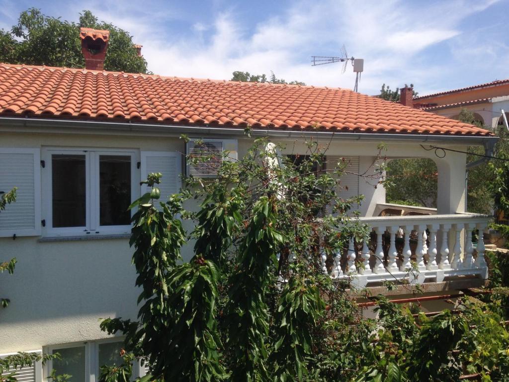 ein Haus mit einem Balkon und einem Baum in der Unterkunft Apartment and Studio Jelušić in Pinezici