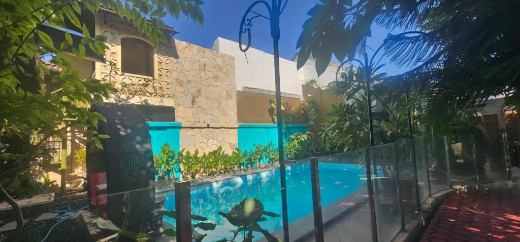 a swimming pool in front of a building with a fence at Bhumi Sammy by Sammy Home Yogyakarta in Timuran