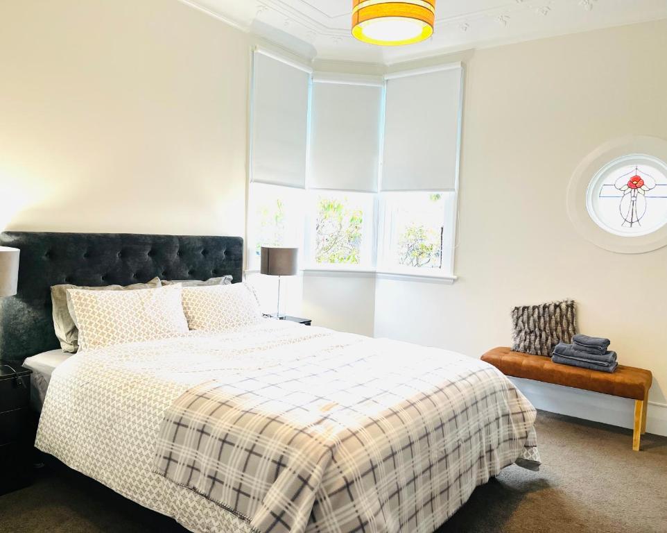 a bedroom with a bed with a checkered blanket at Luxurious Home Close to Beach in Dunedin