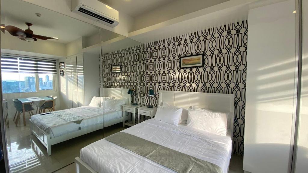 a bedroom with two beds and a wall with black and white wallpaper at Calyx Residences 18i in Cebu City