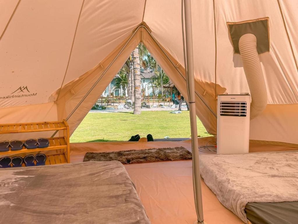 ein Zelt mit einem Bett und einer Klimaanlage in der Unterkunft MUINE SUN & SEA BEACH ( BOUTIQUE RESORT & GLAMPING) in Mui Ne
