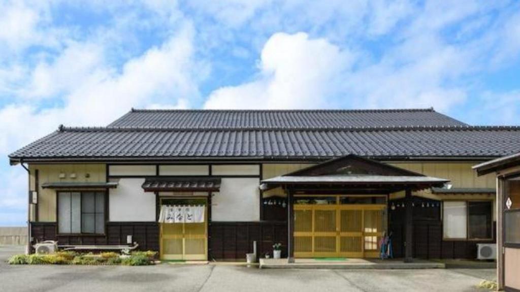 budynek z czarnym dachem i żółtymi drzwiami w obiekcie Sado Ryosou Minato w mieście Sado