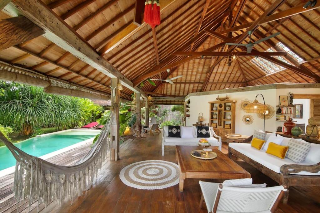 a living room with a couch and a table and a pool at Villa Maia in Kerobokan