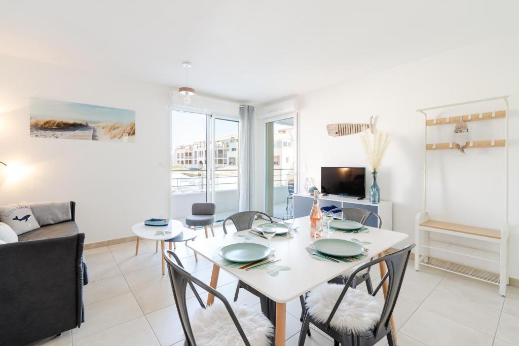 a living room with a white table and chairs at Appartement Neuf 4 étoiles - Sunset Lodge, Narbonne Plage in Narbonne