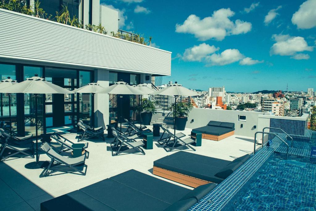a rooftop pool with chairs and umbrellas on a building at Southwest Grand Hotel in Naha