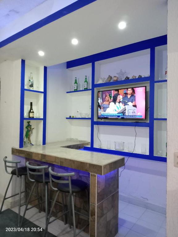 a kitchen with a bar with a tv on a wall at Departamento en playa caleta in Acapulco