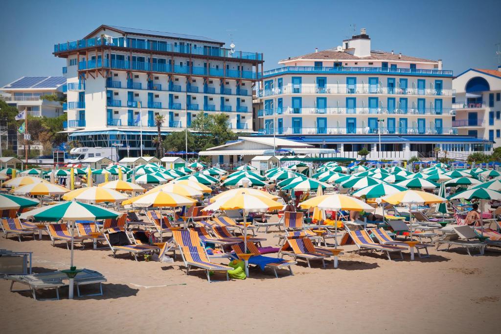 een groep stoelen en parasols op een strand bij Hotel Playa e Mare Nostrum in Caorle