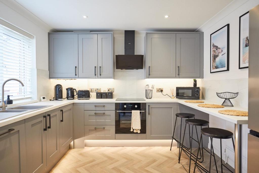 a kitchen with white cabinets and bar stools at Elegant Design 75" Smart Tv Long Stay Welcome in Norwich