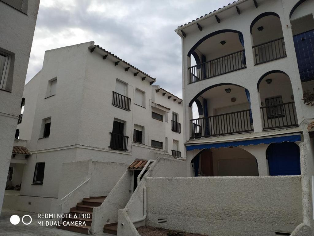 una fila de edificios blancos con balcones y escaleras en Apartamento, 3° línea de playa, en Cubelles