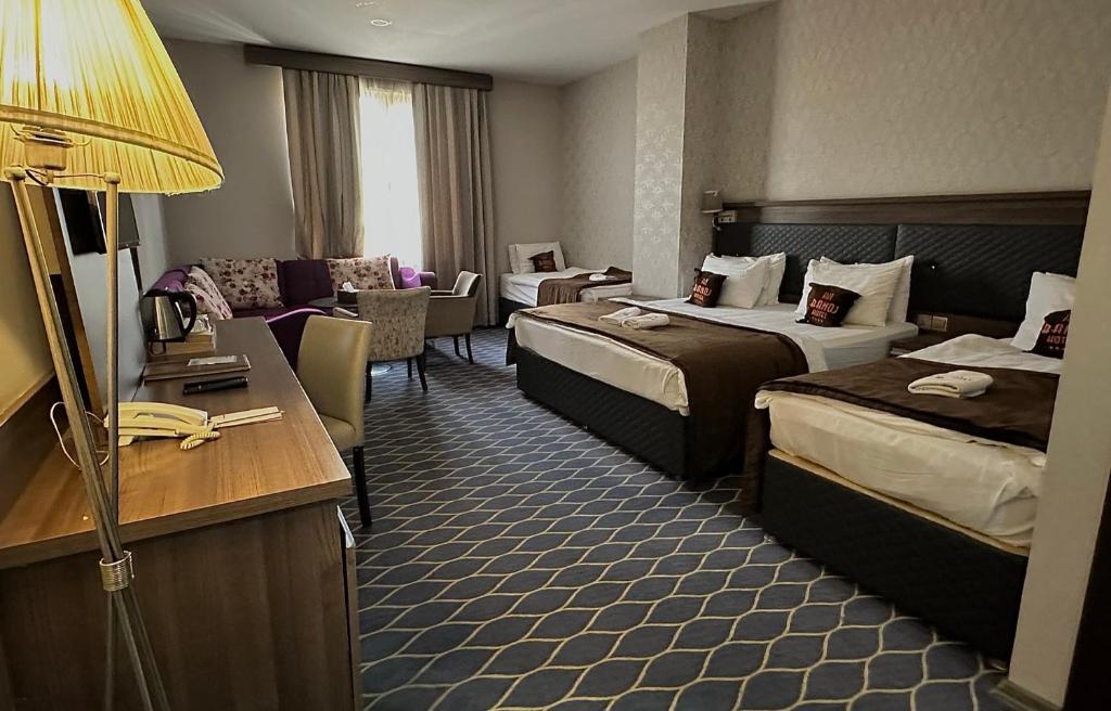 une chambre d'hôtel avec deux lits et un salon dans l'établissement Banoj Hotel, à Erbil