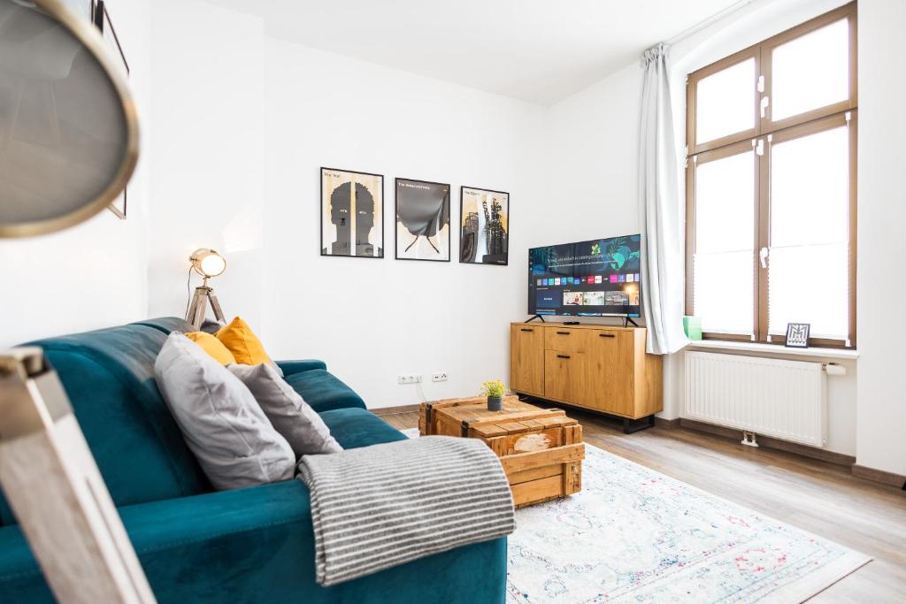 a living room with a blue couch and a tv at Apartments am Neuen Theater - Altstadt - Zentral - Küche - Wifi - Powered by Ko-Living in Halle an der Saale