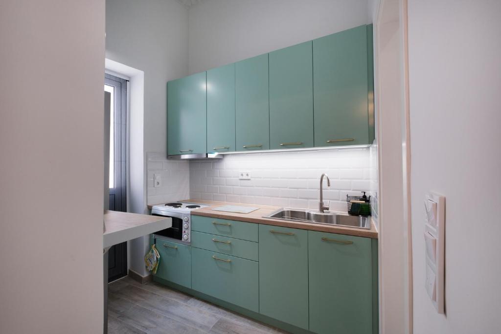a kitchen with green cabinets and a sink at Piraiki Coastal Accommodation in Piraeus