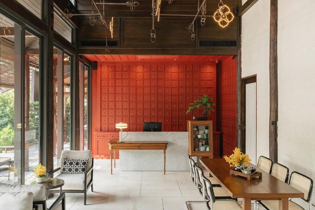 una sala de estar con una pared roja, mesas y sillas en Hotel Loy Chiang Mai en Chiang Mai
