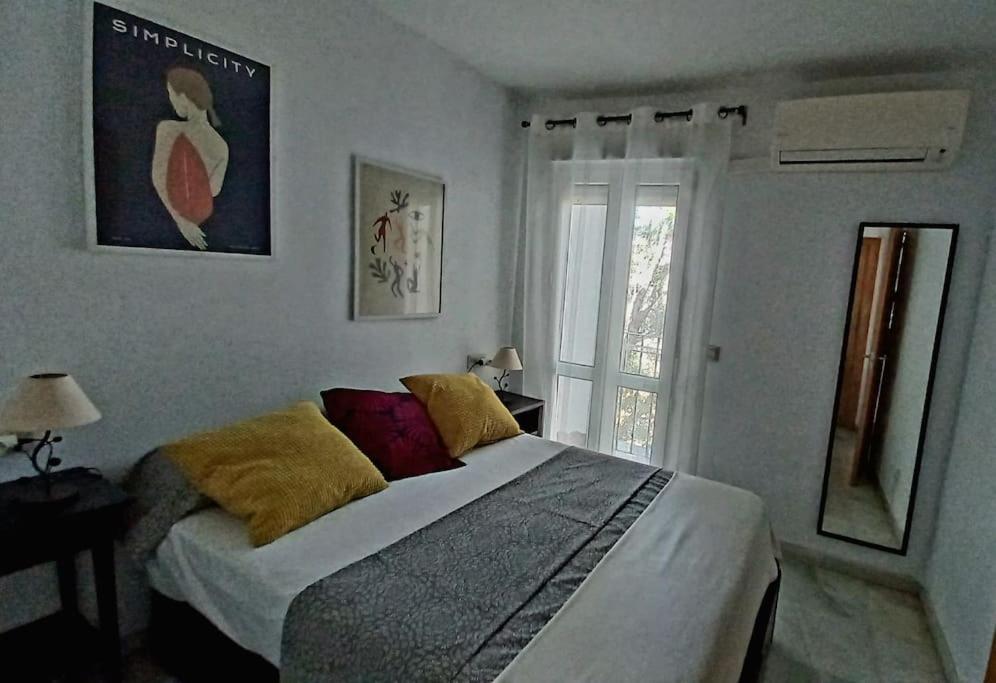 - une chambre avec un lit doté d'oreillers jaunes et d'une fenêtre dans l'établissement Bonito apartamento en centro, à Malaga