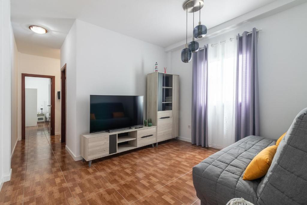 een woonkamer met een bank en een flatscreen-tv bij Flatguest La Herradura in Telde