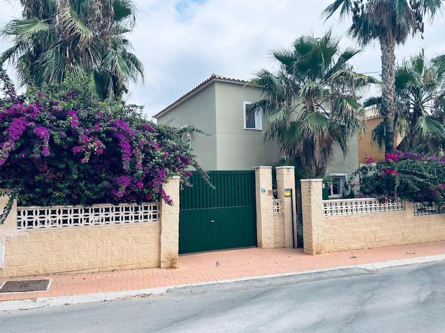 uma casa com um portão verde e flores roxas em Casa Linda La Nucía Park em La Nucía