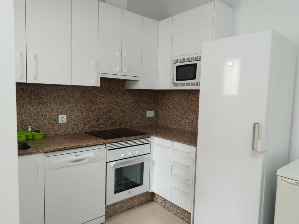 a white kitchen with white cabinets and a microwave at La Casita del pescador in Cabo de Palos