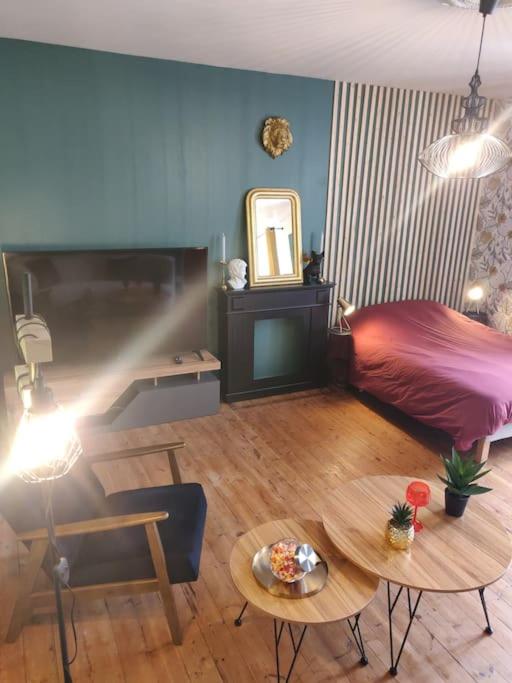 a living room with a bed and a table at De Vert et d'Or - proche gare - parking - jardin in Saint-Brieuc