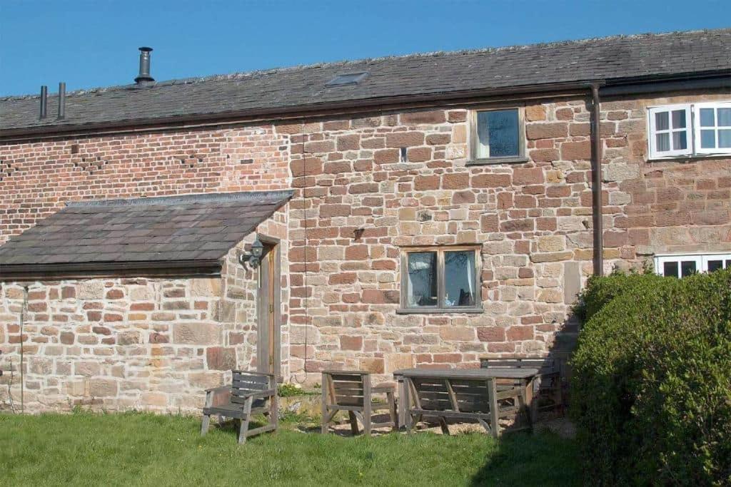 a brick building with a table and chairs in front of it at The Shippon Barn - A delightful haven for families in Wirral