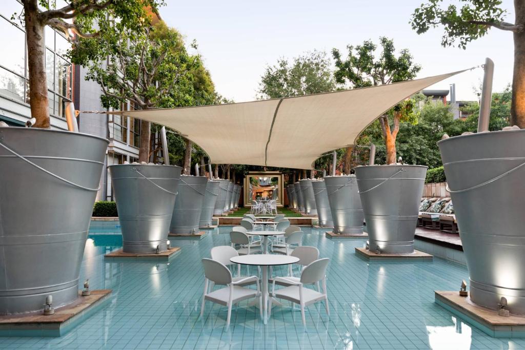 a patio with tables and chairs on a blue tile floor at African Pride Melrose Arch, Autograph Collection in Johannesburg