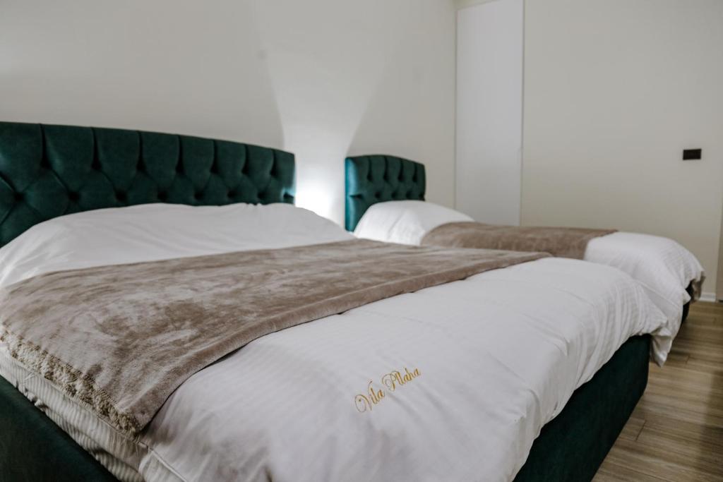 a bedroom with two beds with white sheets and a green headboard at Vila Pllaha in Korçë