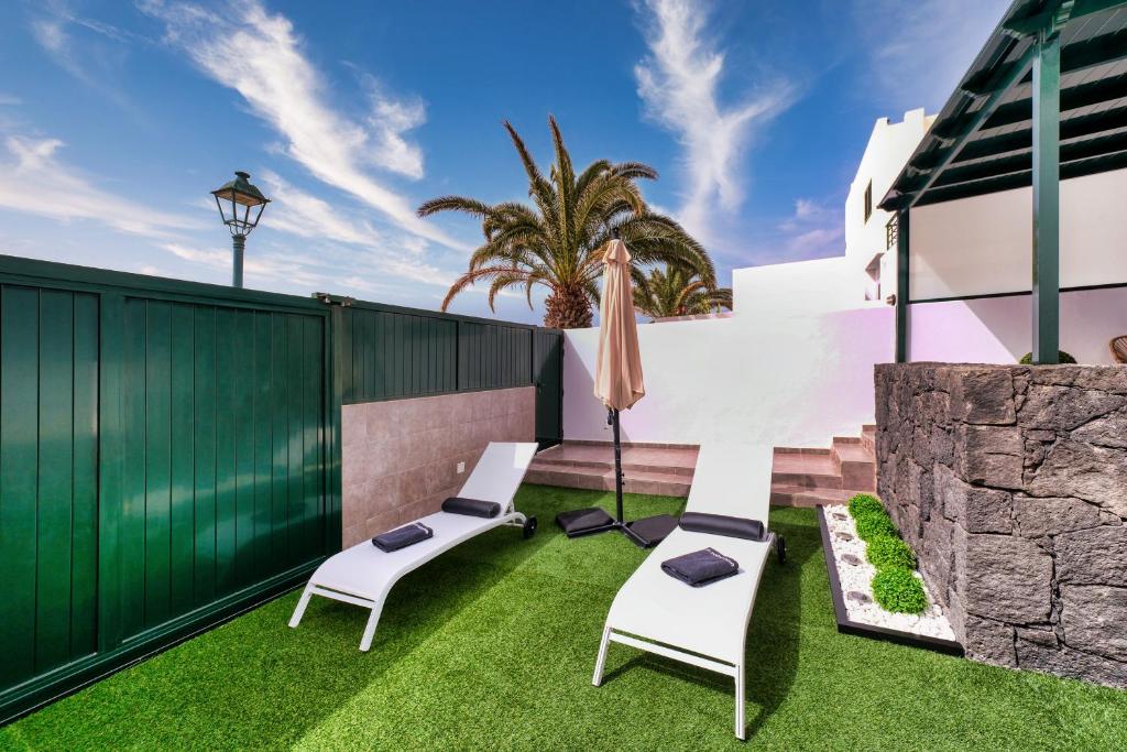 een patio met 2 stoelen en een parasol bij Casa Costa Esmeralda Plus-Pool and Relax in Costa Teguise