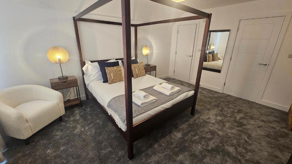 um quarto com uma cama de dossel e uma cadeira em The Oasis, SAV - Romney Sands Beach House em Littlestone-on-Sea