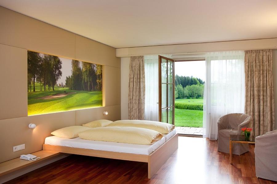 a bedroom with a large bed and a large window at Golfhotel Bodensee in Weißensberg