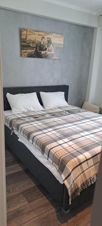 a bedroom with a bed with a plaid blanket on it at Аэропорт Апартаменты 24&24 Parking in Chişinău